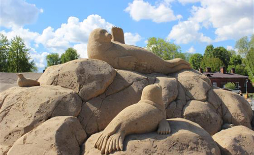 Hiekasta veistetty norppa, joka vilkuttaa evällään