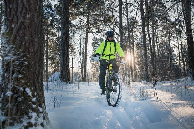 Mies pyöräilemässä talvisessa metsässä.
